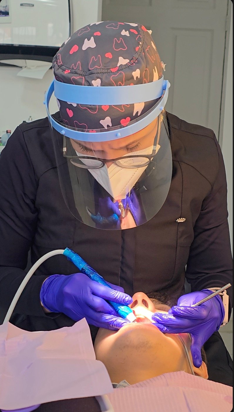 La Dra. Cindy Padilla realizando un tratamiento dental a un paciente en la clínica